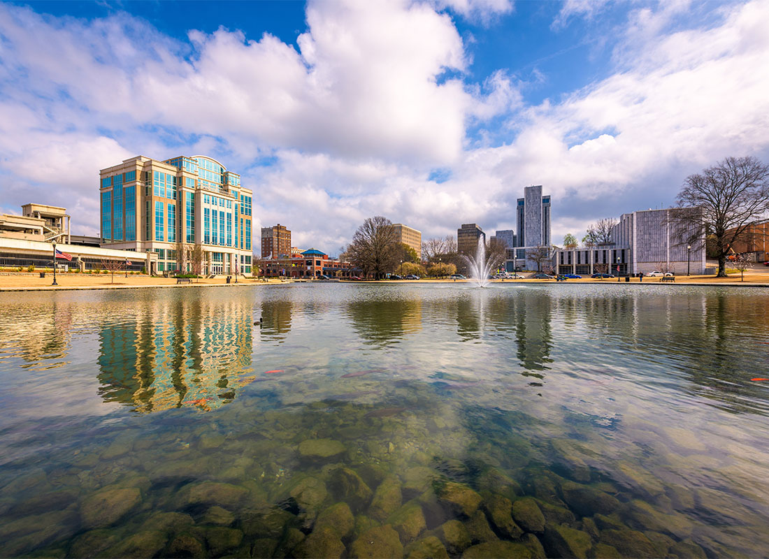 About Our Agency - Scenic View of Rocks in the Water with a Fountain in the Middle and Surrounding Commercial Buildings in the Background on a Sunny Day in Huntsville Alabama