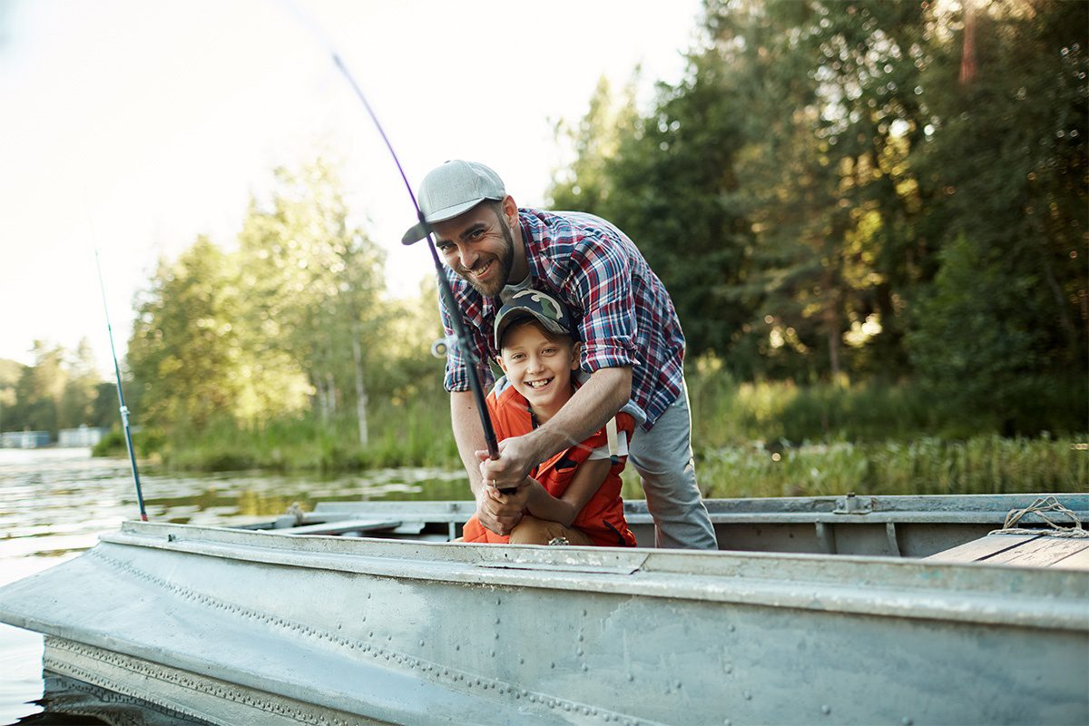 Insurance Solutions - Portrait of a Cheerful Father and Son Having Fun Fishing Together on a Boat in the Lake on a Sunny Afternoon